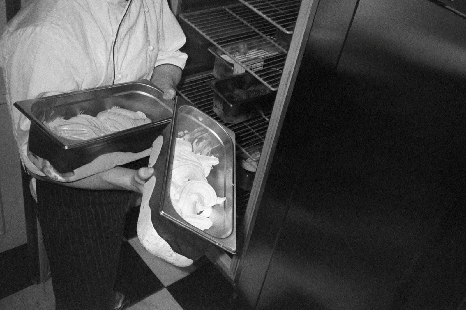 Gelatomakare placerar fyllda kantiner i kylförvaring