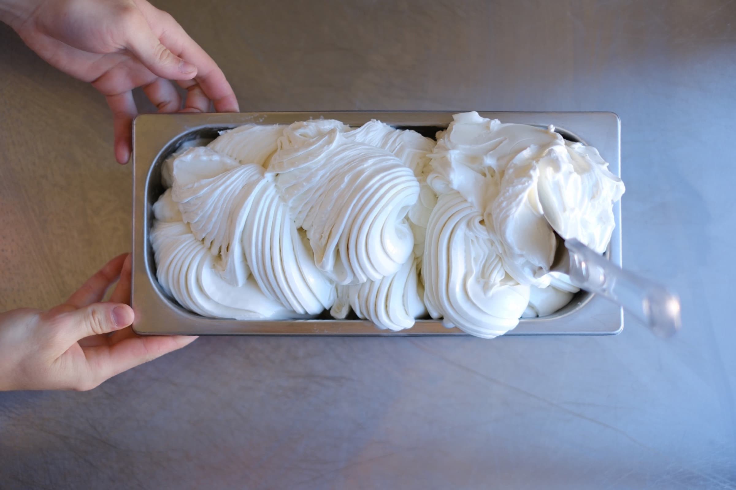 Nyproducerad gelato i en rostfri kantin med händer runt formen